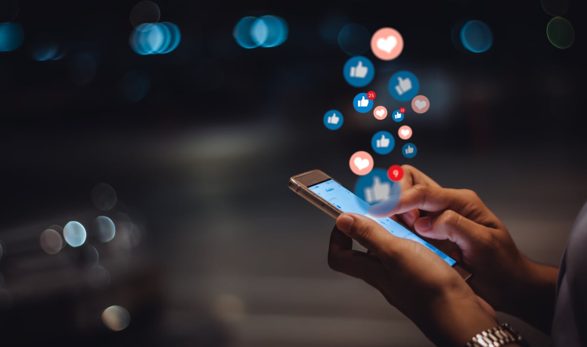 Social media icons floating up from a smartphone.