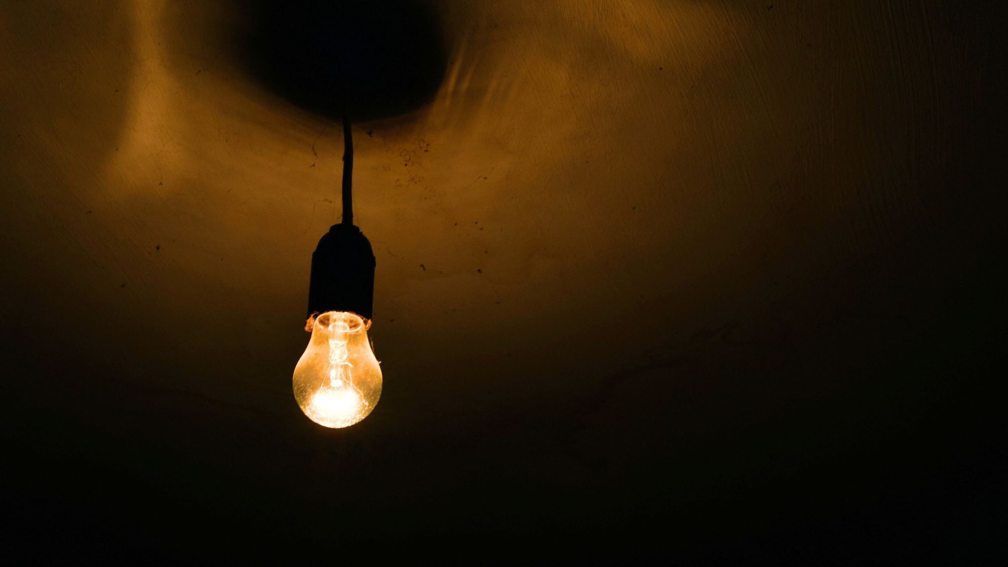 A burning incandescent lamp in a dark basement on the ceiling