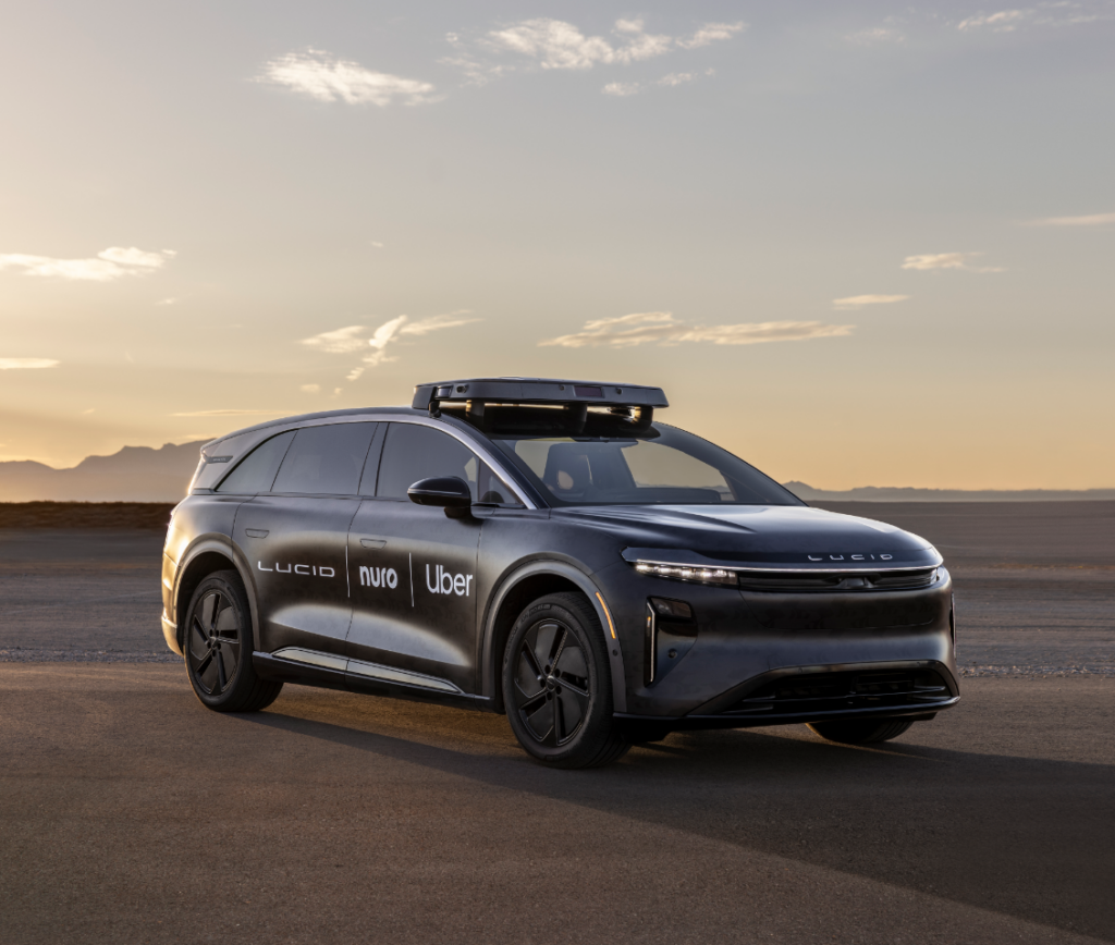 A black Lucid robotaxi with Lucid, Nuro, and Uber logos on it, at dawn or dusk.