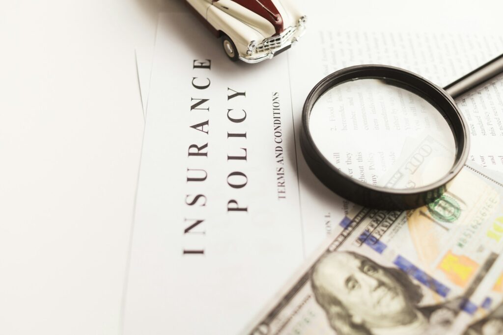 a magnifying glass sitting on top of a piece of paper; car insurance rates under 25