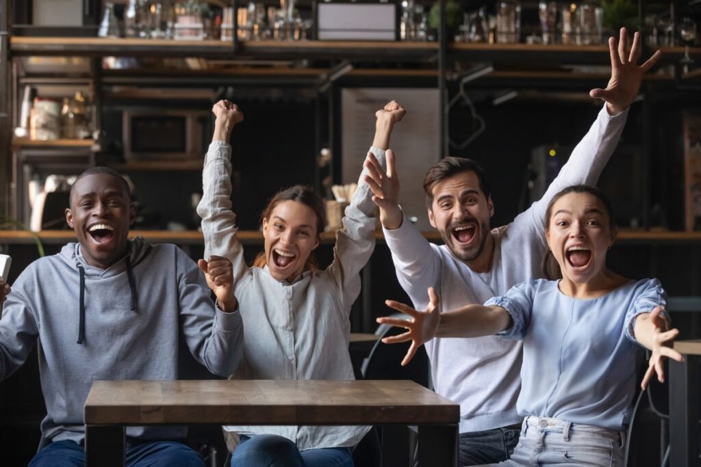 Four people seated at a table cheering and smiling.