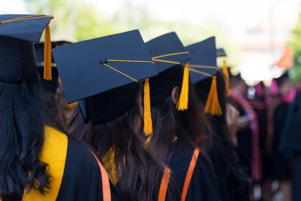 Rear view and soft selective focus of the graduates in the graduation commencement ceremony receiving diploma degree certificate.