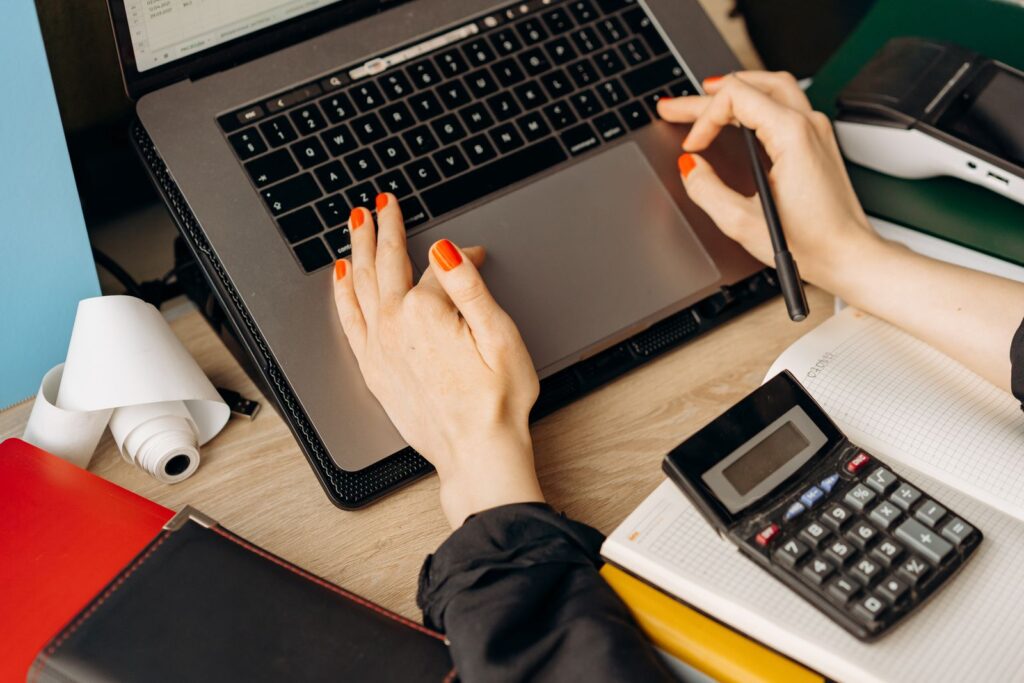 A company director reviewing the books on a laptop with a calculator during the first financial year