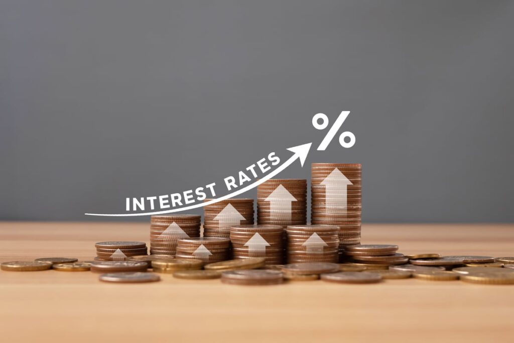 A stack of coins with up arrows and a label that says "interest rates."